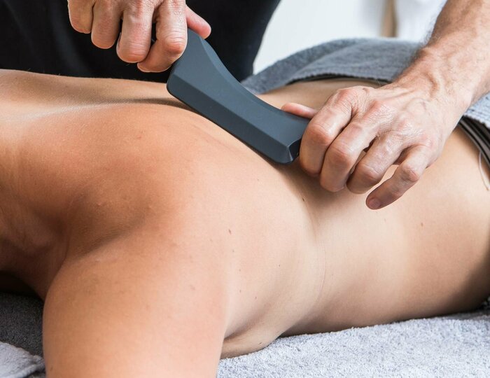 A woman receives a sport special massage at Kristall Spa while her back is treated with a massage device.