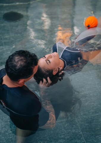 Eine Frau liegt im Wasser, während eine Spa-Behandlung im Kristall Spa von Hotel Hochschober durchgeführt wird.