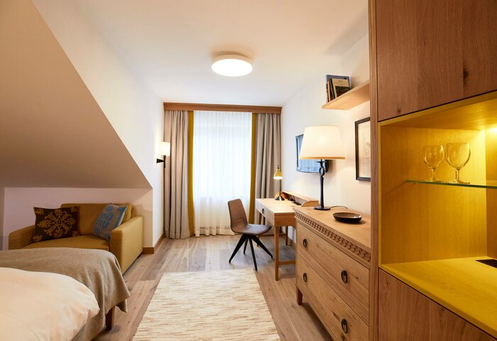 Classic studio room at Hotel Hochschober A classic studio room with a bed, sofa, desk and warm wooden furniture, facing the window and balcony.