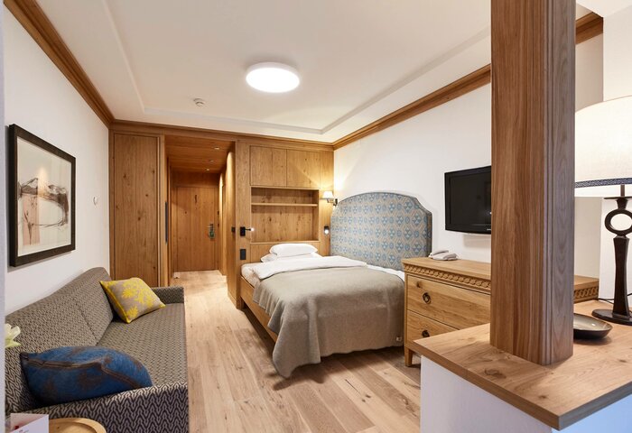 Single room at Hotel Hochschober with wood details A single room with a bed, sofa, wood paneling and desk in Hotel Hochschober.