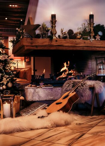 A decorated Christmas tree and a lit fireplace define the festive Bergweihnacht setting.