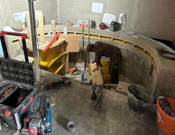 Umbau der Hotelbaustelle im Hotel Hochschober Ein Handwerker arbeitet in einer runden Hotelbaustelle mit Werkzeugen, Eimern und Baumaterialien im Innenraum.