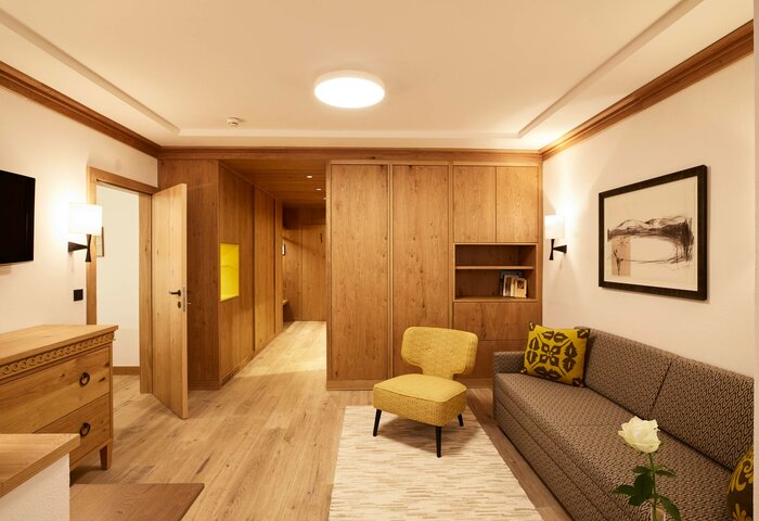Superior studio double room at Hotel Hochschober A superior studio double room with wood paneling, a seating area, sofa and open doorway at Hotel Hochschober.