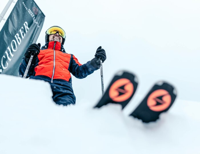 Ski special on Turracher Höhe A skier in a red jacket stands in deep snow beside a ski lift mast.