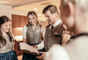 Vier Mitarbeitende im Hotel Hochschober schauen gemeinsam in eine Mappe und besprechen Unterlagen.