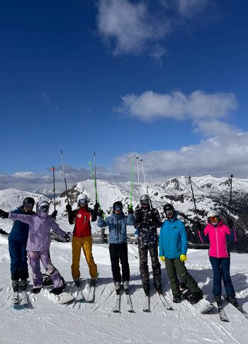 Skifahrer in der Winterlandschaft auf der Turracher Höhe Sechs Skifahrer stehen auf einer verschneiten Piste vor Berggipfeln und halten ihre Skier in die Luft.