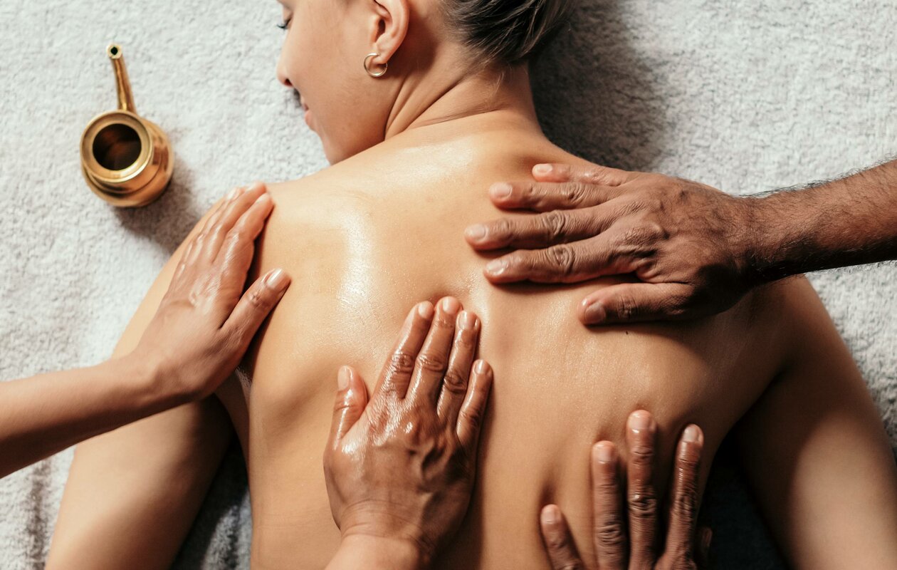 Eine Frau liegt bei einer Massage im Kristall Spa, während mehrere Hände ihren Rücken behandeln.