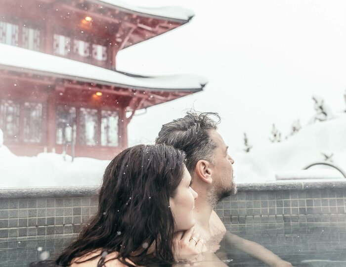Wellnessurlaub im Outdoor-Pool am Chinaturm Ein Paar sitzt im warmen Außenpool vor dem roten Chinaturm im Schnee.