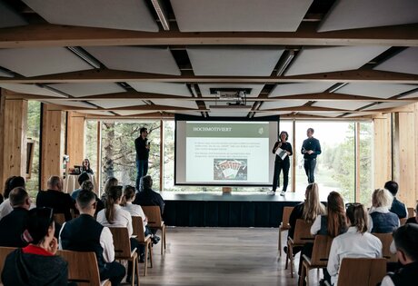 In einem Seminarraum im Hotel Hochschober hält eine Person vor sitzendem Publikum eine Präsentation.