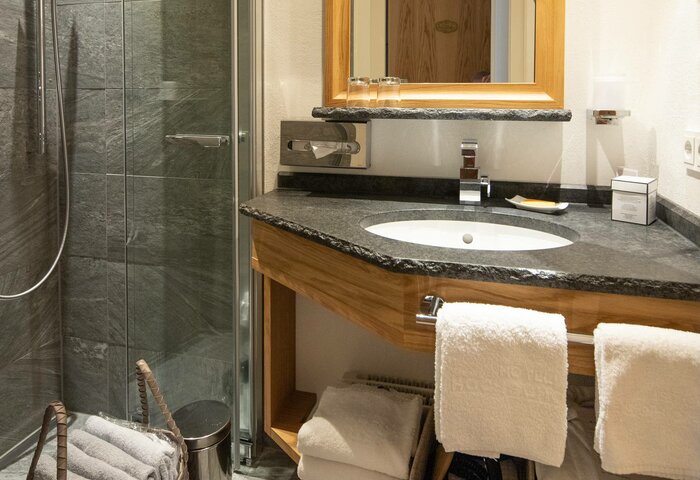 A bathroom with shower, washbasin, mirror and towels in the Erker maisonette apartment.
