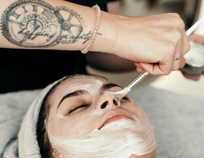 A beautician applies cream to the face of a reclining woman during a facial treatment at Kristall Spa.