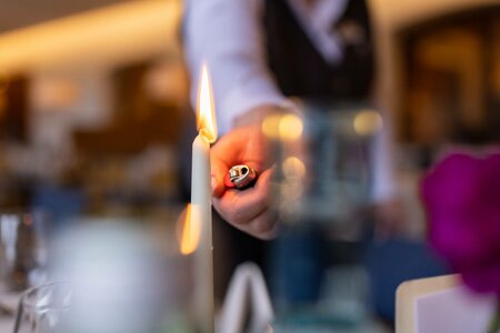Eine Hand zündet eine Kerze auf einem gedeckten Tisch im Restaurant an.