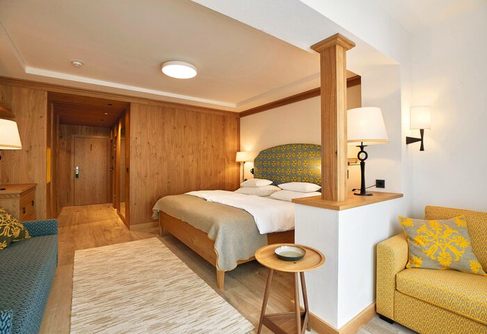 Ein Superior Studio Doppelzimmer mit Holzwänden, Bett, Sitzecke und warmen Lichtakzenten.