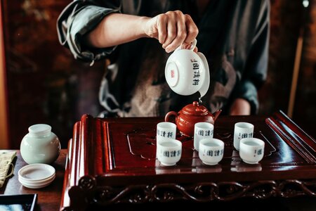 Eine Hand gießt beim Tee im Chinaturm des Hotel Hochschober auf einem traditionellen Tablett.