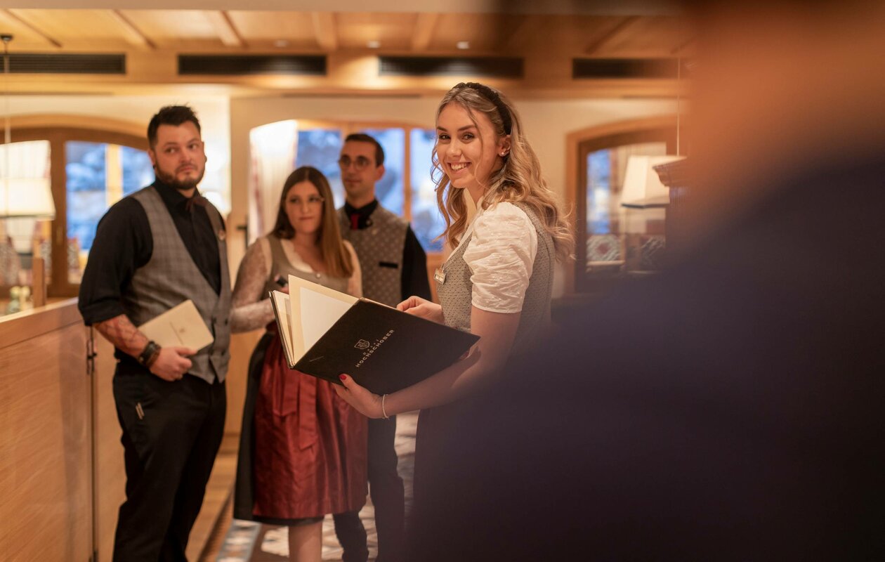 Vier Mitarbeitende im Hotel Hochschober stehen in einem Innenraum und halten Unterlagen in der Hand.