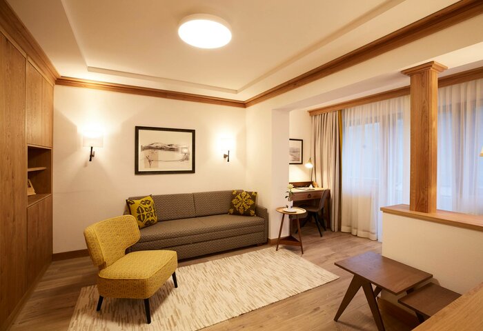 Ein stilvoll eingerichteter Wohnbereich eines Superior Studio Doppelzimmers mit Sofa, Sessel, Schreibtisch und Holzdetails.