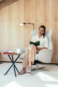 Eine Frau sitzt in einem Sessel und liest ein Buch in der Bibliothek des Hotel Hochschober.