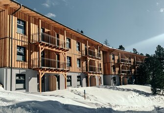 Ein modernes Gebäude mit mehreren Balkonen steht im Schnee, vermutlich die Mitarbeiterunterkunft des Hotel Hochschober.