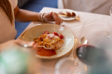 Ein Teller mit Pasta und Tomatensauce steht auf einem gedeckten Tisch im Hotelrestaurant.