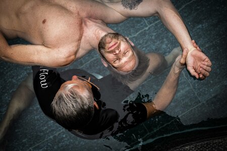 Ein Mann liegt entspannt im Wasser, während eine Person ihn im Spa des Hotel Hochschober sanft hält und begleitet.