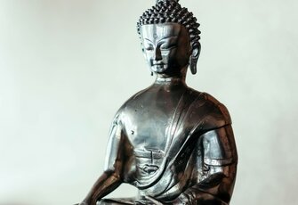 Eine Buddha-Statue steht vor einer hellen Wand und prägt die ruhige Atmosphäre des Yoga-Raums im Hotel Hochschober.