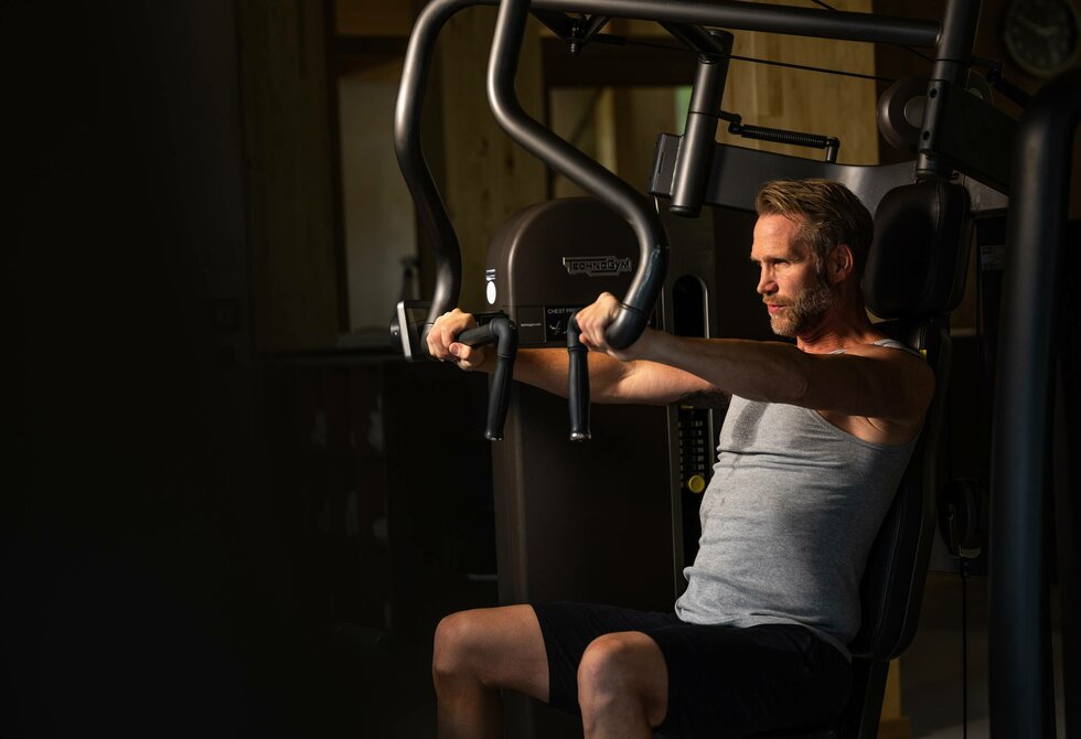 Ein Mann trainiert an einem Kraftgerät im Fitnessraum des Hotel Hochschober.
