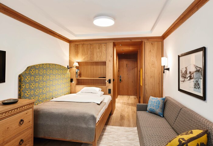 Single room at Hotel Hochschober with wood details A single room with wood paneling, a bed, sofa and warm materials at Hotel Hochschober.