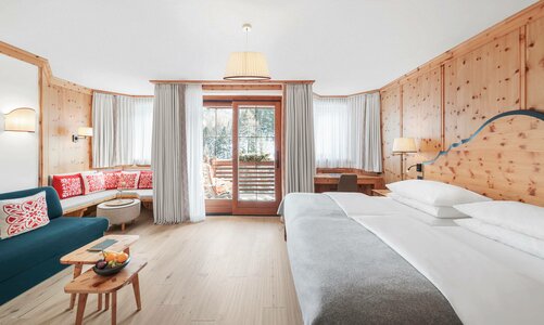Ein helles Hotelzimmer mit Doppelbett, Sitzbank, Sofa und Balkonblick im Hotel Hochschober.