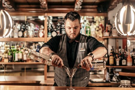 Ein Barkeeper mixt an der Hotelbar zwei Getränke in ein Cocktailglas.