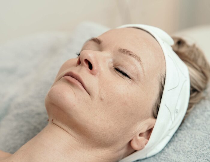 A woman lies relaxed with a headband during a facial treatment at the Kristall Spa.