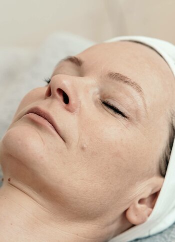 Eine Frau liegt mit Stirnband entspannt bei einer Gesichtsbehandlung im Kristall Spa.