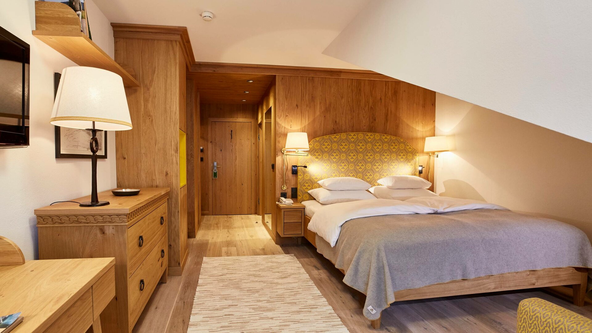 A classic studio room with a double bed, wooden furniture and warm neutral tones.