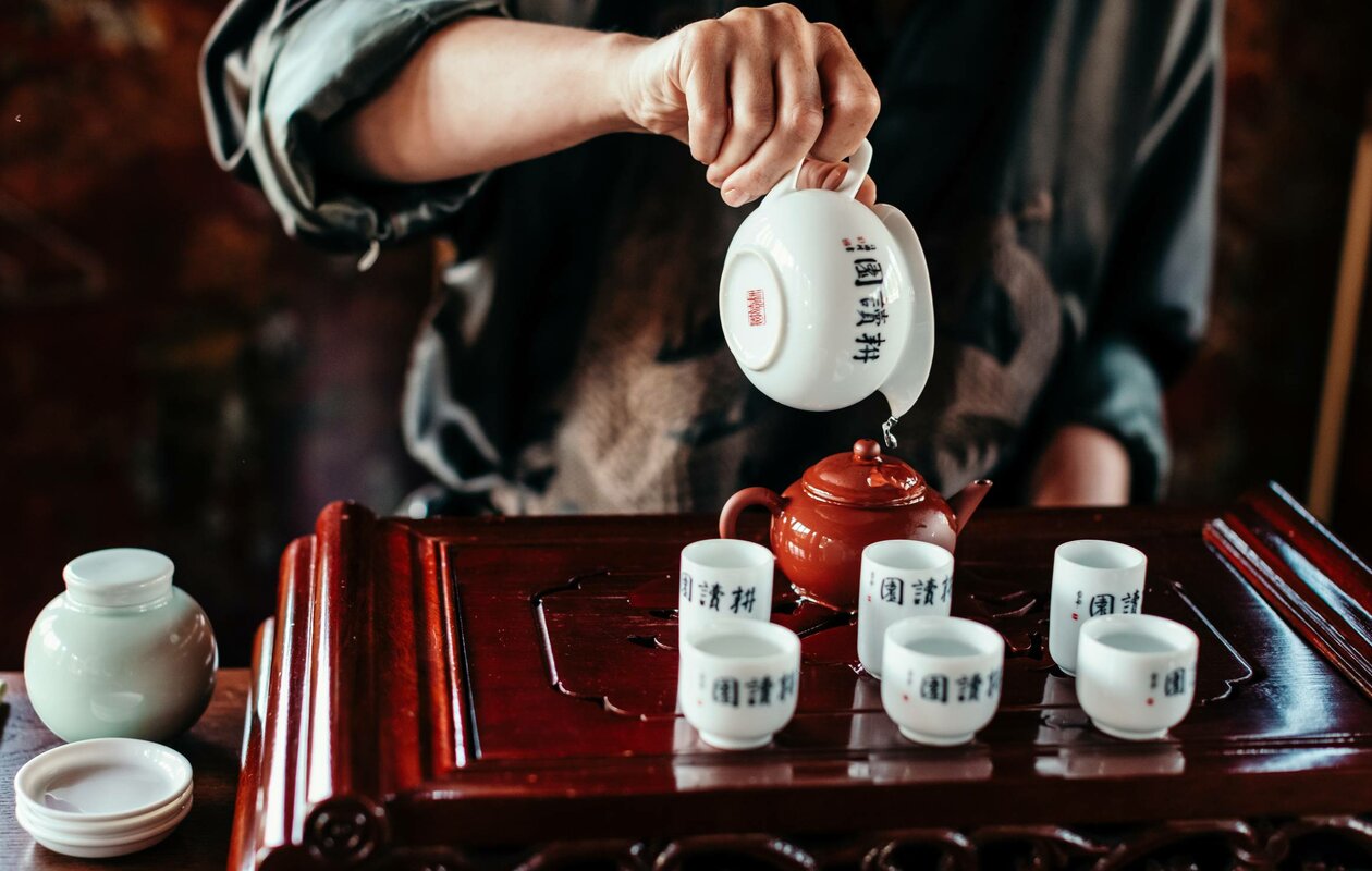 Eine Hand gießt Tee in kleine Tassen auf einem Teetablett im Chinaturm des Hotel Hochschober.