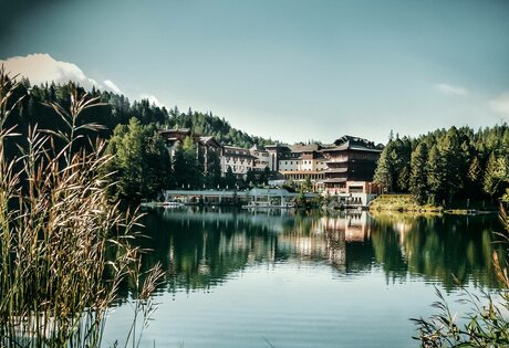 Hotel Hochschober stands on the shore of Turracher Lake, framed by forested mountains on the Turracher Höhe.