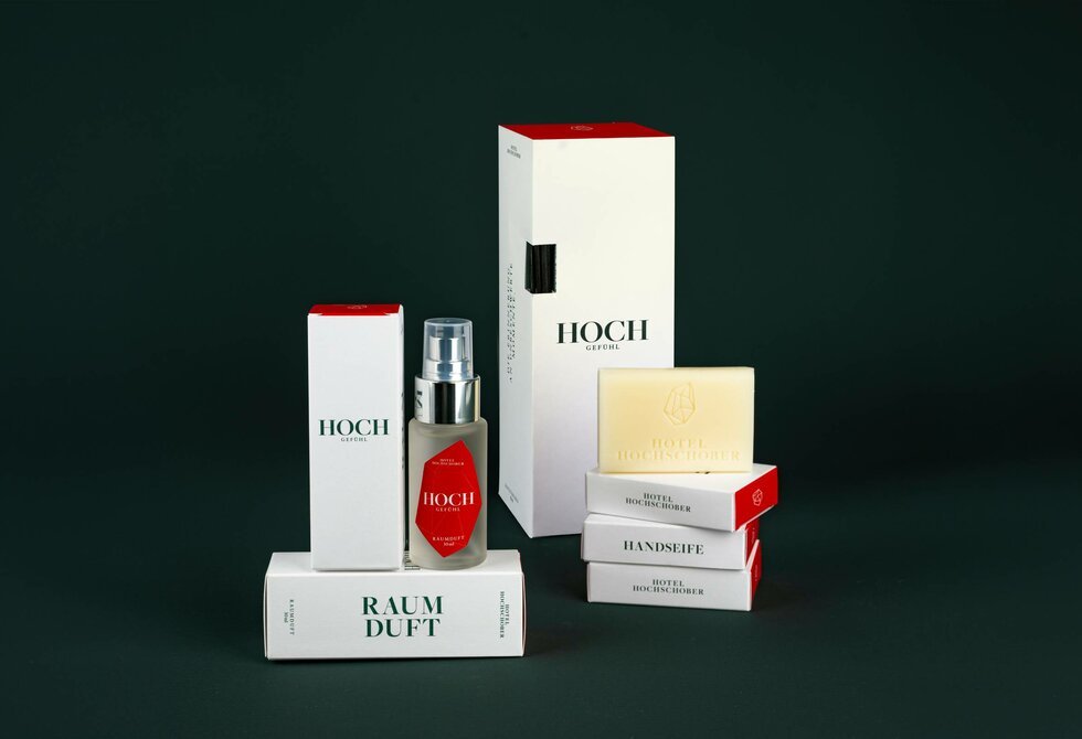 Several HOCH care products and scent boxes are arranged against a dark green background.