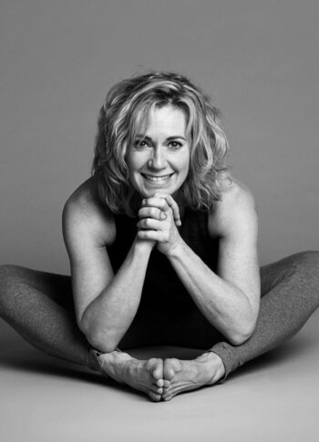Yoga-Pose im Hotel Hochschober Eine Frau sitzt in einer Yoga-Pose auf dem Boden und lächelt in die Kamera.