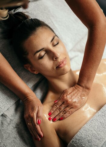 A woman receives a relaxing wellness massage while lying on a treatment table.