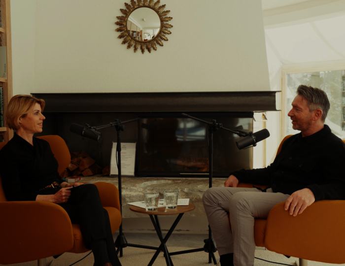 Interview im Hotel-Lesebereich am Kamin Eine Frau und ein Mann sitzen sich in einem Hotel-Lesebereich vor dem Kamin gegenüber und sprechen in Mikrofone.