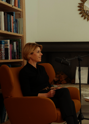 Interview im Hotel-Lesebereich am Kamin Eine Frau und ein Mann sitzen sich in einem Hotel-Lesebereich vor dem Kamin gegenüber und sprechen in Mikrofone.