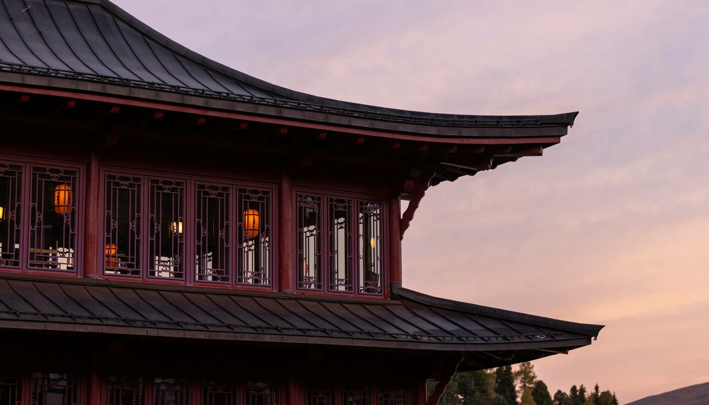 Der Chinaturm mit chinesisch inspirierter Architektur leuchtet im Abendlicht über dem Hotel Hochschober.
