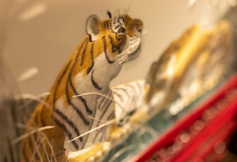 Eine Tigerfigur steht in einer chinesisch gestalteten Innenansicht mit warmem Licht und dekorativen Elementen.