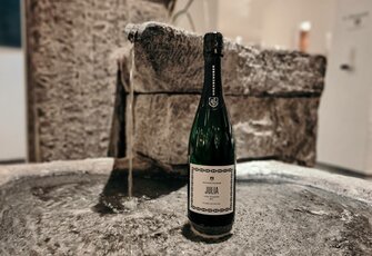 A sparkling wine bottle labeled “Julia” stands on a stone fountain in the hotel shop.