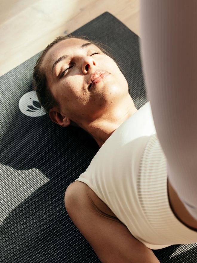 Eine Frau liegt auf einer Yoga matte mit geschlossenen Augen