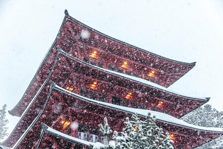 Der rote Chinaturm des Hotel Hochschober steht bei starkem Schneefall zwischen verschneiten Bäumen.