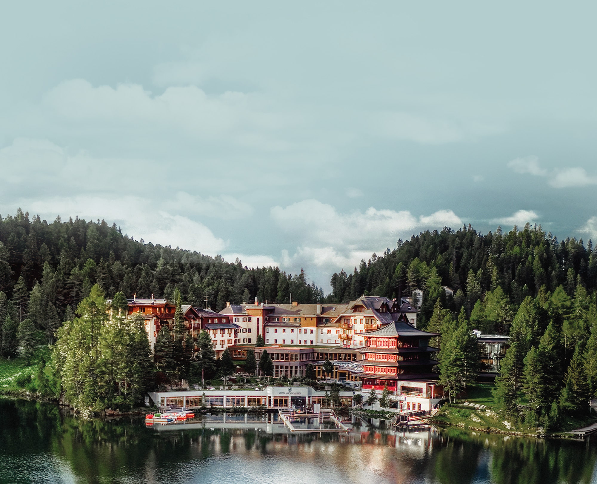 Hotel Hochschober stands on the shore of Lake Turracher See, framed by forested hills and calm water.
